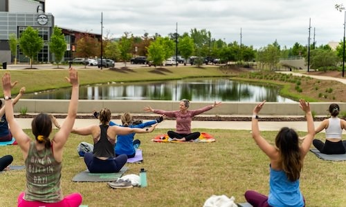 people doing yoga outside in front of a pond