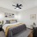 Bedroom with king sized bed, wood plank flooring, and ceiling fan.