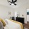 Bedroom with king sized bed, wood plank flooring, ceiling fan, and door leading to hallway